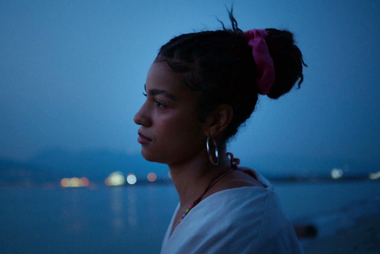 A woman in profile by the water at blue hour